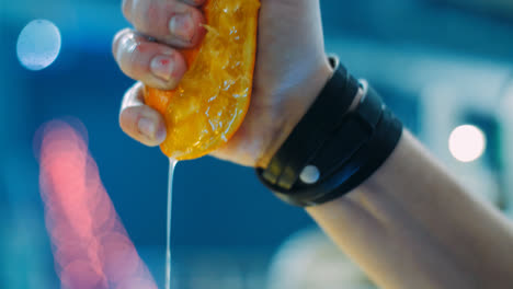Barman-squeezing-orange-into-glass-during-preparation-of-cocktail