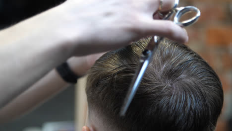 Barber-cutting-man-with-scissors-under-comb.-Man-having-hair-cut-in-barbershop