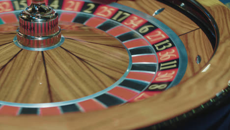Closeup-of-wooden-roulette-wheel-rotating-in-foreground.-Table-in-luxury-casino