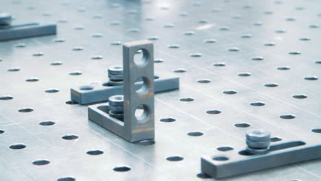 Fasteners-on-working-surface-of-industrial-unit.-Metallic-plate-with-holes