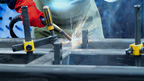 Man-welding-metallic-blanks-in-workshop-of-metalworking-plant