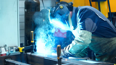 Worker-making-welding-of-metal-surfaces-producing-many-bright-flashes-and-sparks