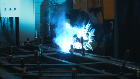 Metal-welding-process-in-dark-industrial-room.-Metal-steel-structure-in-workshop