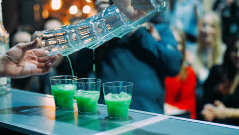 Bartender-masterly-making-three-green-cocktails-at-same-time-at-nightclub
