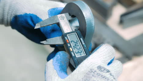 Worker-measuring-inner-diameter-of-iron-part-with-electronic-caliper