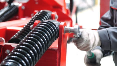 Worker-tightening-nut-on-shock-absorber-of-agricultural-unit-with-socket-wrench