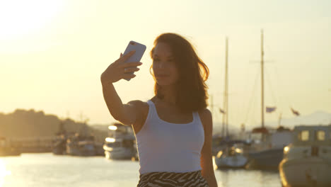 Glückliche-Frau,-Die-Im-Abendhafen-Ein-Handyfoto-Macht.-Reisemädchen-Posiert-Für-Selfie