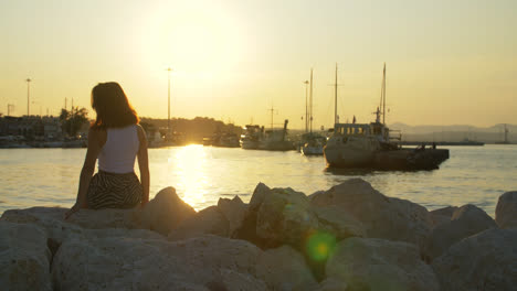 Tourist-girl-on-stone-at-evening-sunset-in-sea-port.-Woman-on-sunset-landscape