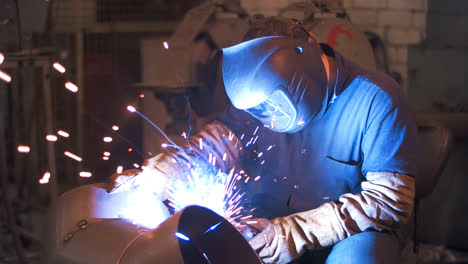 Industrial-worker-welding-steel-in-protective-mask-at-metalworking-factory