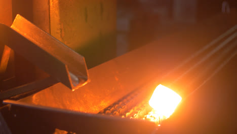 Glowing-detail-from-molten-metal-moving-on-conveyor-line-at-metallurgy-plant