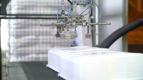 Robotermanipulator-Bewegt-Kunststoffbehälter-In-Der-Fabrik-Auf-Das-Förderband
