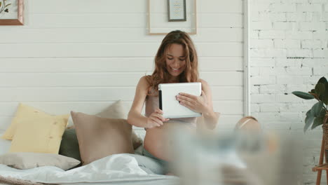 Pregnant-woman-talking-video-chat-bed.-Expectant-mother-holding-tablet-at-home