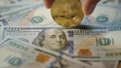 Bitcoin-Mining-Konzept.-Menschliche-Hand-Dreht-Goldbit-Münze-Auf-Dollar-Banknoten
