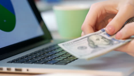 Woman-hand-counting-dollar-bills-on-laptop-keyboard.-.-Online-business-money