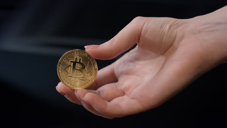 Woman-hand-holding-gold-bitcoin-coin.-Bitcoin-business-concept.-Bitcoin-in-hand