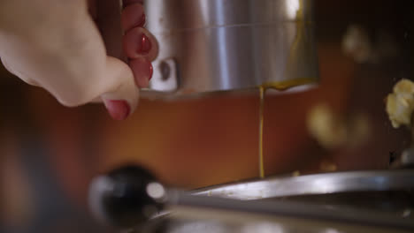Female-hand-pouring-oil-into-machine-for-popcorn-production