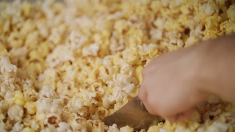 Human-hand-pouring-ready-popcorn-from-popcorn-machine-by-ladle