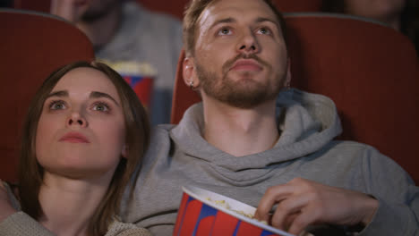 Close-up-of-young-people-faces-watching-movie-at-cinema-theater