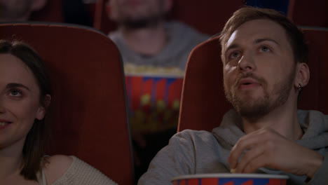 Joyful-people-watching-movie-in-cinema-and-eating-popcorn