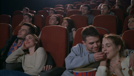 Love-couples-watching-movie-at-movie-theater.-Young-people-eating-popcorn