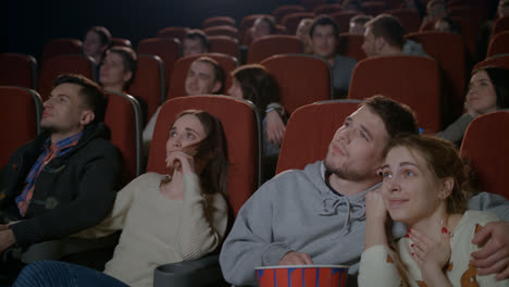 Love-couples-watching-movie-in-cinema.-Young-couple-embracing-in-movie-theater