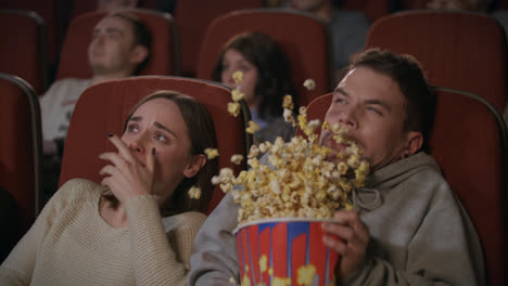 Young-couple-watching-horror-film-in-movie-theatre.-Guy-sprinkle-popcorn