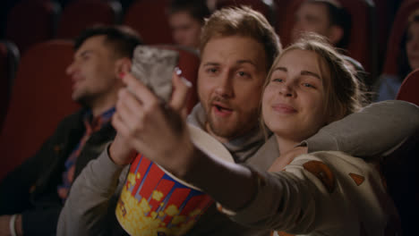 Girl-making-selfie-photo-with-boyfriend-at-cinema.-Love-couple-taking-photo