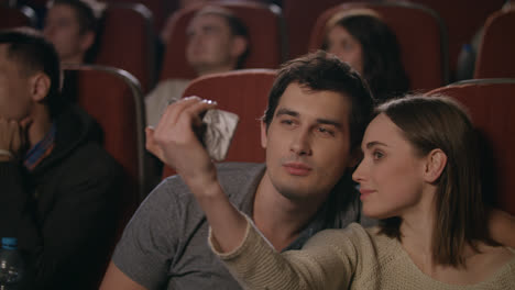 Kiss-selfie-in-cinema.-Happy-couple-making-selfie-in-cinema