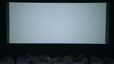 Spectators-applaud-in-anticipation-of-movie-session-in-front-of-white-screen