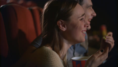 Young-couple-enjoying-film-in-cinema.-Couple-eating-popcorn-and-watching-movie