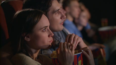 Young-couple-eating-popcorn-from-one-box.-Fiends-couple-watching-movie
