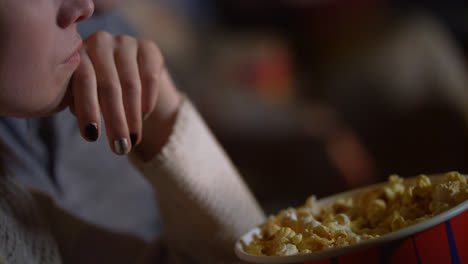 Girl-taking-popcorn-from-paper-bucket-to-mouth.-Woman-eating-pop-corn-at-cinema