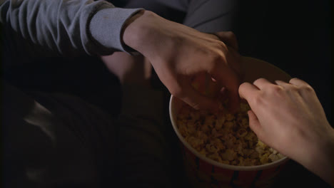 Female-and-male-hand-take-popcorn-grains-from-popcorn-box-in-slow-motion