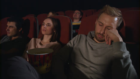 Man-sleep-at-cinema-movie.-Guy-sleeping-at-cinema-date.-People-watch-boring-film