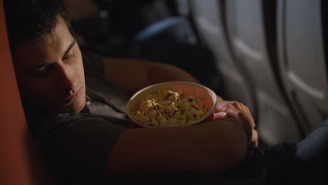Sleeping-man-embracing-popcorn-box-at-cinema.-Guy-sleeping-in-chair-at-cinema