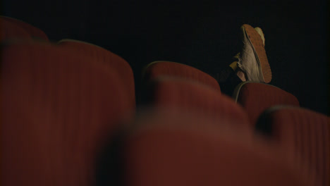 Man-sleeping-in-empty-cinema-hall.-Sleeping-man-feet-on-cinema-chair
