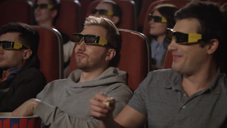 Friends-eating-popcorn-in-movie-theater.-People-watching-movie-in-3d-glasses