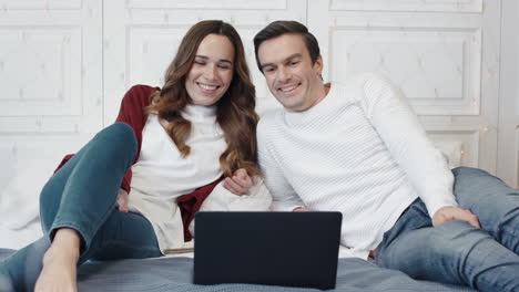 Happy-couple-watching-movie-on-computer-at-home-together.