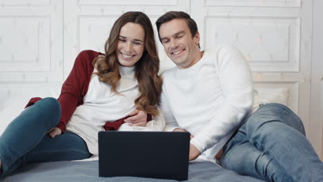 Happy-family-laughing-in-front-of-laptop-screen-in-living-room.