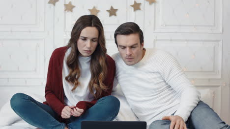 Upset-couple-watching-horrible-news-on-computer-at-home-together.