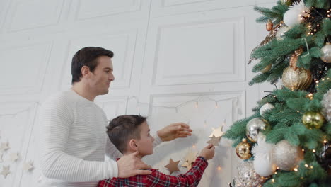 Smiling-father-decorating-living-room-with-son-together.