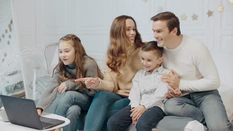 Smiling-family-watching-funny-video-at-notebook-together