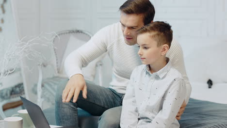 Smiling-father-and-son-chatting-on-laptop-computer-in-luxury-house.