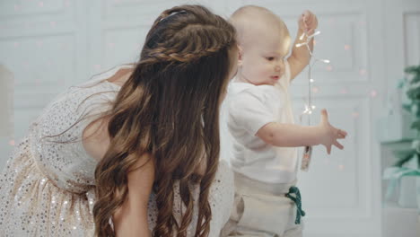 Cute-baby-boy-playing-garland-in-living-room.-Pretty-sister-caring-small-brother