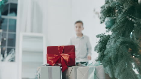 Closeup-young-guy-taking-gift-near-christmas-tree-in-luxury-house.