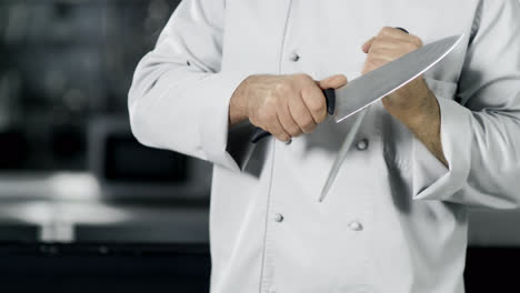 Chef-hands-sharpening-knife-in-slow-motion.-Closeup-hands-cook-food-at-kitchen.