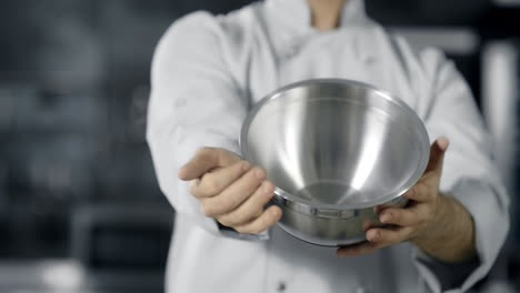 Professional-chef-playing-with-kitchen-tools.-Close-up-chef-hands-rolling-bowl