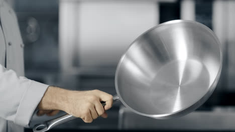Chef-hands-rotating-wok-at-kitchen.-Closeup-man-hands-playing-with-wok.