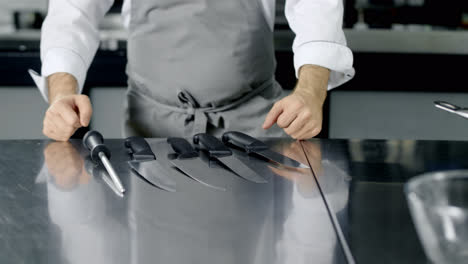 Chef-preparing-to-cook-at-kitchen.-Closeup-man-hands-laying-knives.
