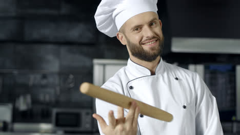 Chef-man-posing-with-roller-at-kitchen.-Smiling-chef-playing-with-roller-pin